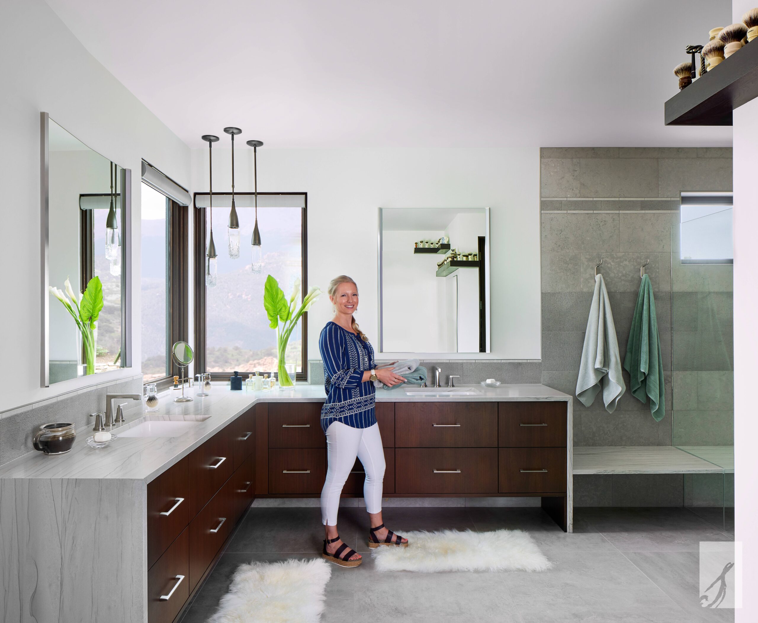 Principal Designer Courtney Sikora in the Contemporary Reflections primary bath showcasing the stone backsplash and finishing features