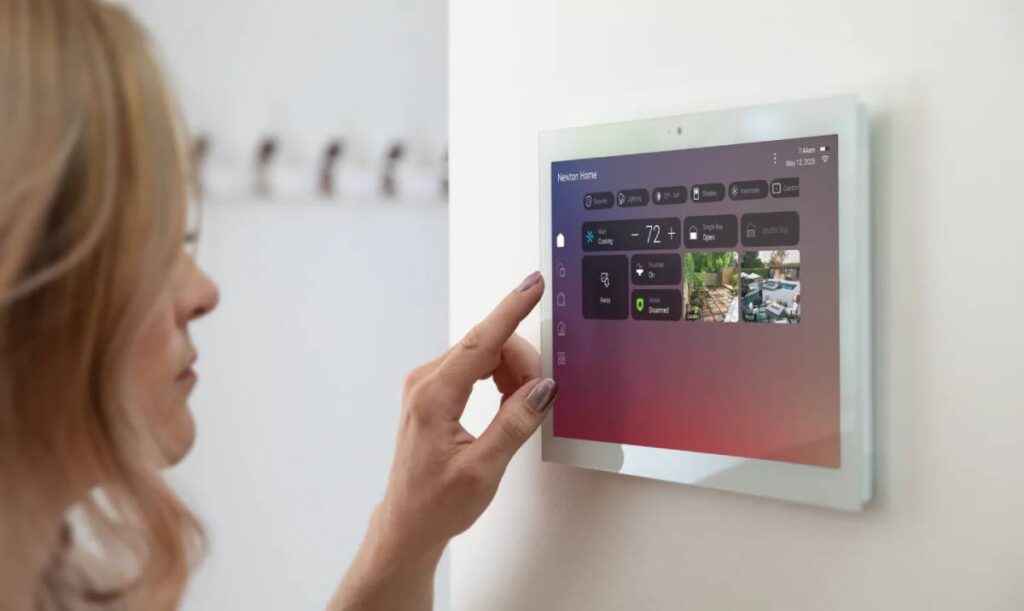 A homeowner using a Control4 system via a wall-mounted touchscreen for whole home automation