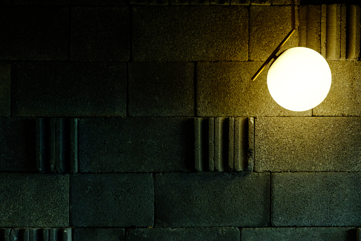 A detail of specialty wall finish paired with a custom light fixture