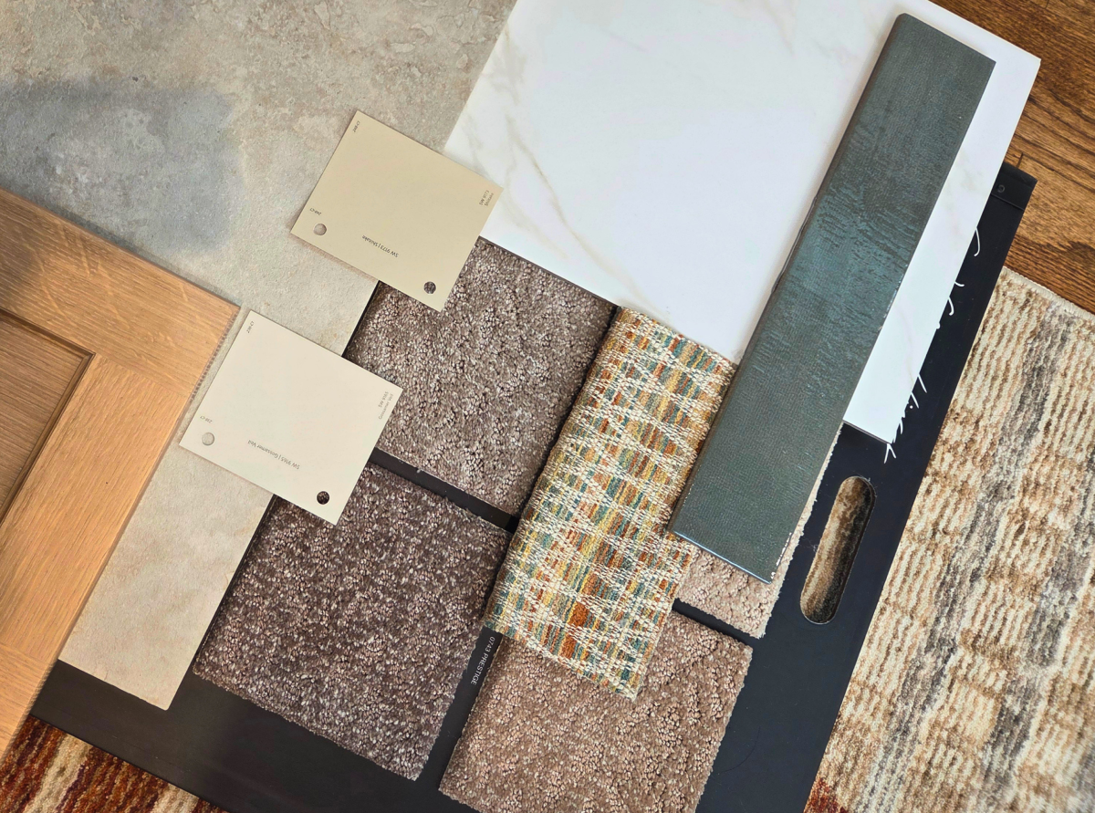 A flat lay of paint samples, carpet swatches, and fabric options during a design refresh
