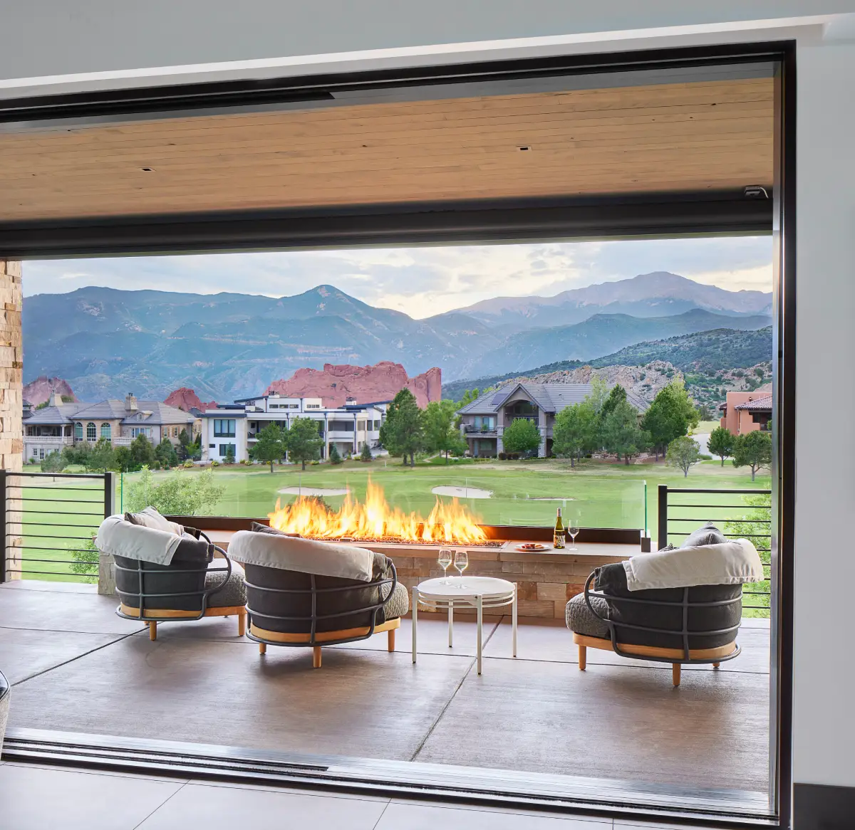 A bifold door fully retracted between an interior and the patio and modern horizontal fire feature
